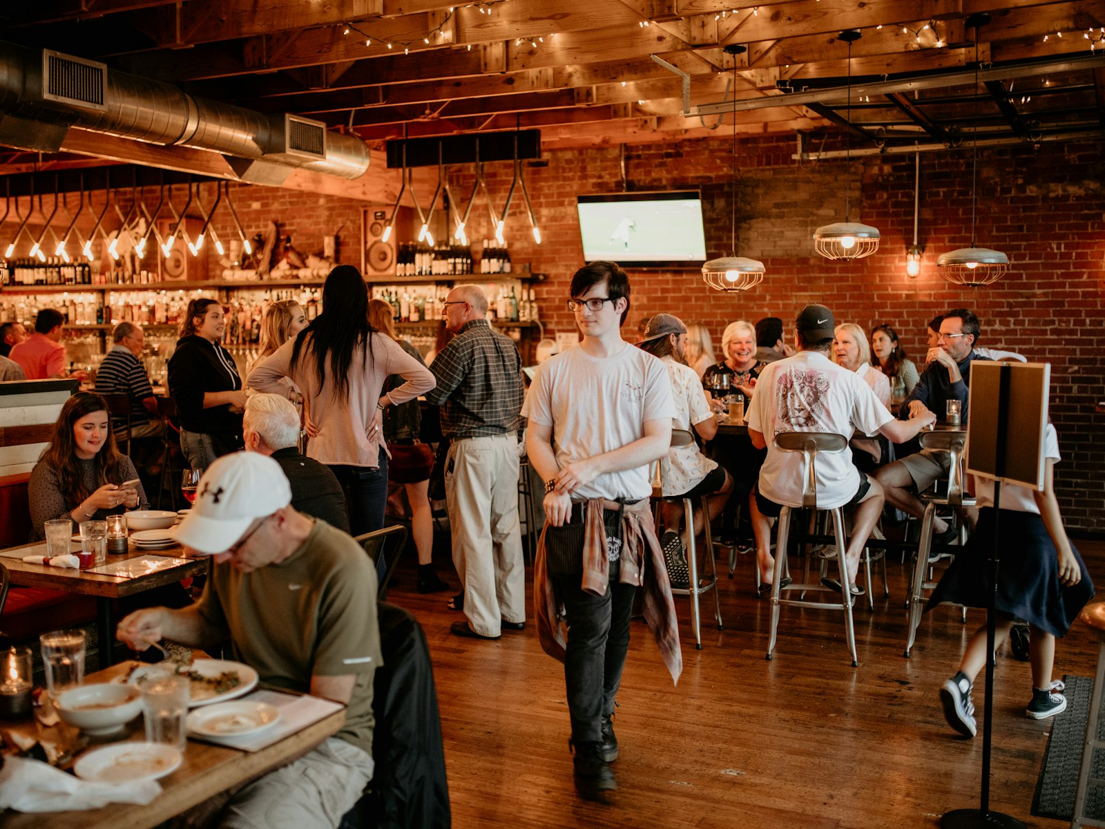 A full taproom under the unit's exposed ductwork and brick